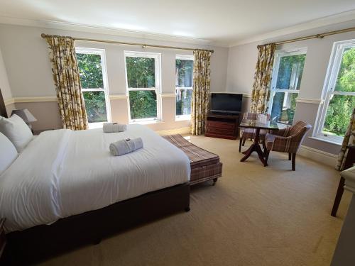 a bedroom with a bed and a desk and windows at The Dower House Hotel in Woodhall Spa