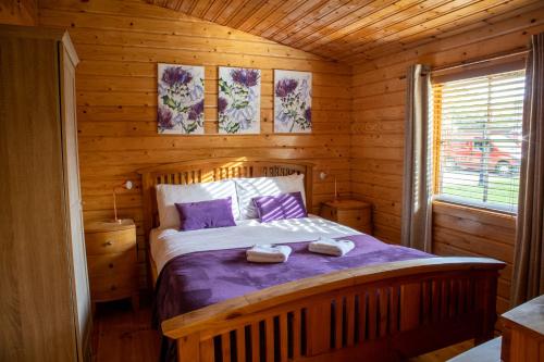 a bedroom with a bed in a wooden cabin at The Steadings Log Cabins in Kettlebridge