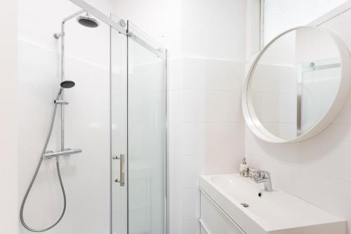 een badkamer met een douche, een wastafel en een spiegel bij Balcony Oasis Operastreet in Wenen
