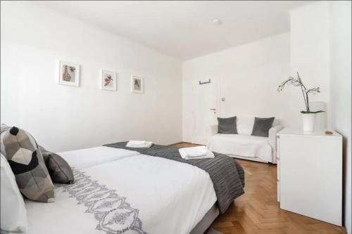 een witte slaapkamer met een groot bed en een bank bij Balcony Oasis Operastreet in Wenen