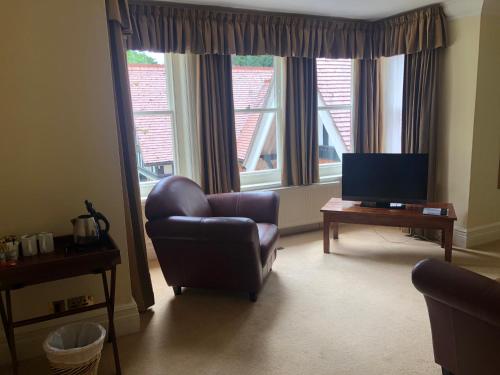 a living room with a chair and a television at The Dower House Hotel in Woodhall Spa