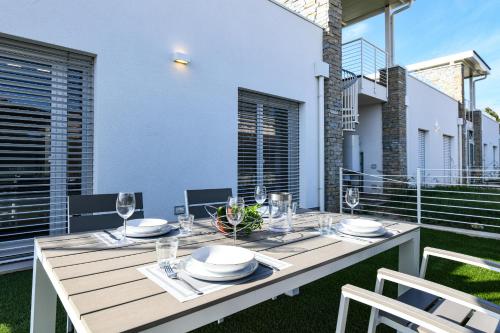a wooden table with plates and wine glasses on a balcony at Villette Dolci Luxury Homes in Peschiera del Garda