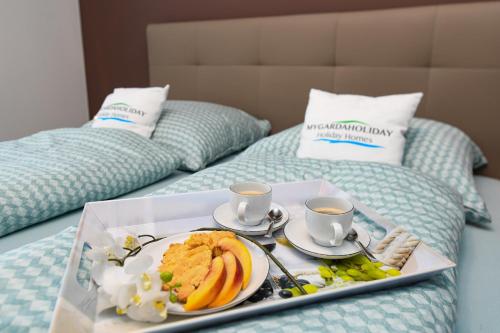a tray of food on a bed with two cups of coffee at Villette Dolci Luxury Homes in Peschiera del Garda