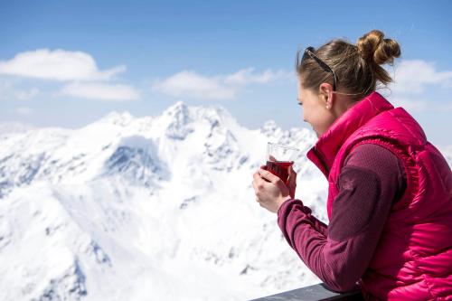 a woman holding a glass of wine in front of mountains at Smart Hotel Firn in Madonna