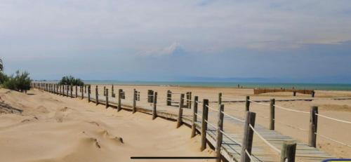 a beach with a wooden fence in the sand at Casa La Gavina in Riumar