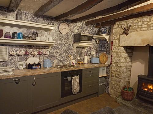 a kitchen with a stove and a stone wall at Longbridge Cottage in Shepton Mallet