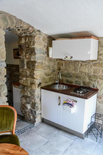 a kitchen with a sink and a stone wall at CASA LUCERTOLA in Apricale