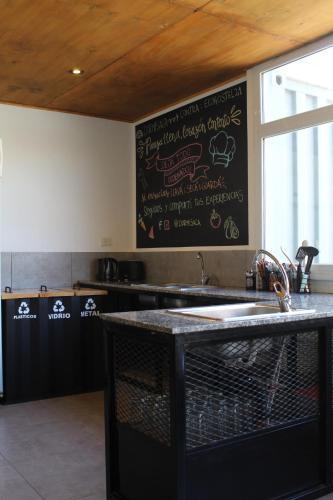 a kitchen with a sink and a chalkboard on the wall at Dormís Acá in Esquel
