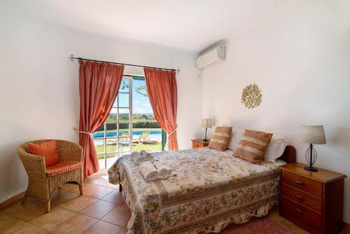 - une chambre avec un lit, une fenêtre et une chaise dans l'établissement Casa do Barrocal, à Almancil
