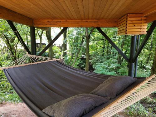a hammock hanging from a roof in a forest at Węgiełek Treehouse in Kazimierz Dolny