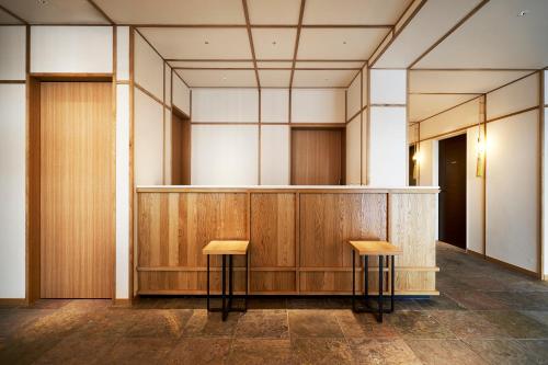 une salle d'audience avec deux tabourets devant un podium dans l'établissement Tassel Inn Kyoto Kawaramachi Nijo, à Kyoto