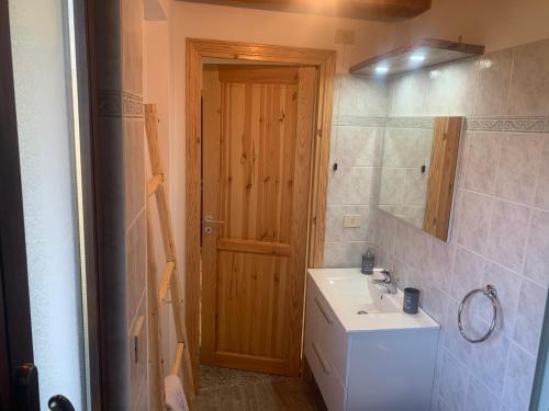 łazienka z umywalką, lustrem i drzwiami w obiekcie Ul baitin da In Re w mieście Craveggia