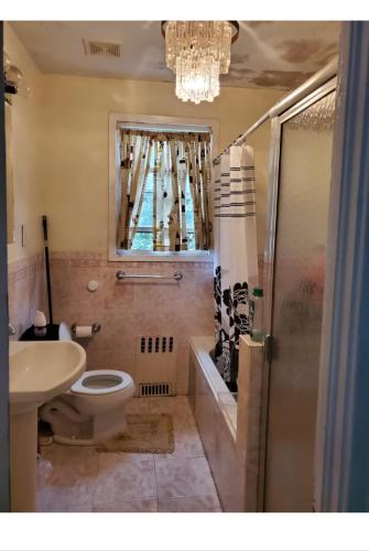 a bathroom with a toilet and a sink and a chandelier at Royalbluecozy in Saint Albans