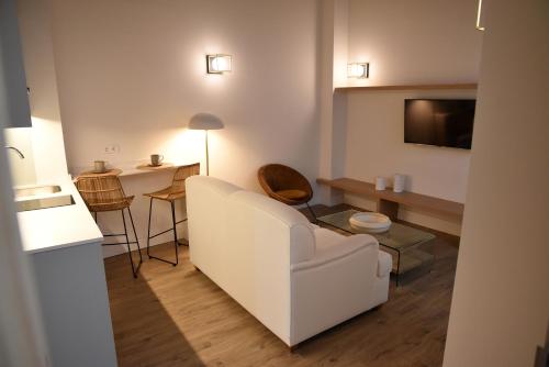 a living room with a white couch and a tv at Casa Bailen Sevilla in Seville