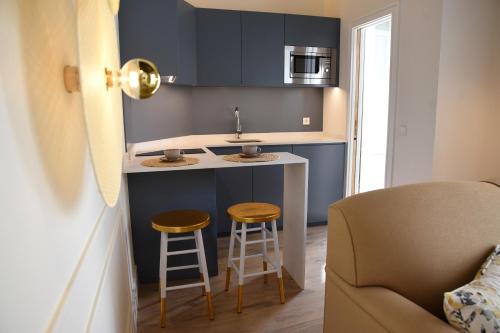 a small kitchen with a sink and two stools at Casa Bailen Sevilla in Seville
