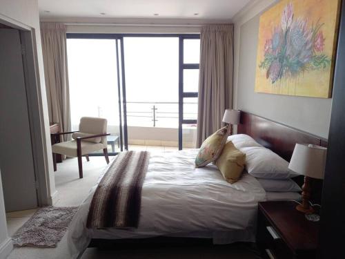 a bedroom with a large bed and a large window at Beachfront Apartment in Cape Town