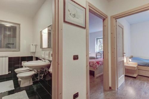 a bathroom with a sink and a toilet and a bed at Residence La Contea in Bormio