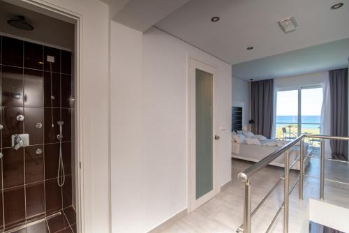 a bathroom with a walk in shower and a bedroom at Belussi Beach Hotel & Suites in Kipseli