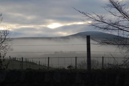 a fence in a field with a mountain in the background at Columba House in Kingussie
