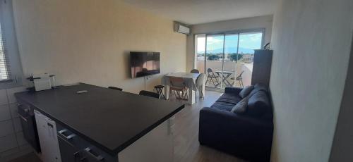 une cuisine et un salon avec un canapé et une table dans l'établissement RESIDENCE DE LA PLAGE Appart à 2 pas de la plage et du marché, à Saint-Cyprien