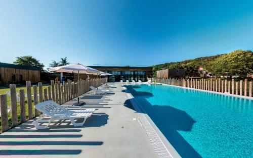 a row of lounge chairs next to a swimming pool at Dives-sur-Mer le Conquérant in Dives-sur-Mer