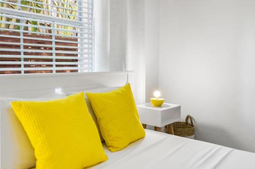 a white bed with yellow pillows and a window at Alani Bay Villas in Fort Lauderdale