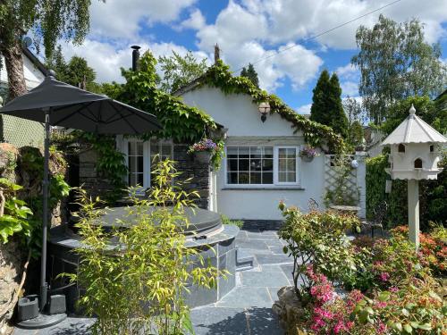 a house with an umbrella and a bird house at Marys Cottage, Grasmere, Dog Friendly, Hot Tub in Grasmere
