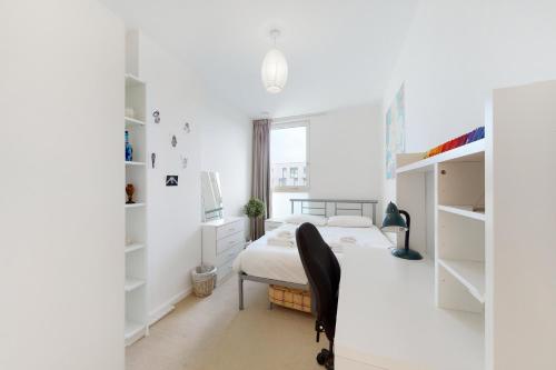 a white bedroom with a bed and a desk at Lovely 2 bedroom flat with balcony in Stratford in London