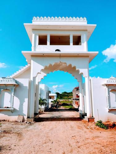 an entrance to a white building with an archway at Vijayam Resort in Nāthdwāra