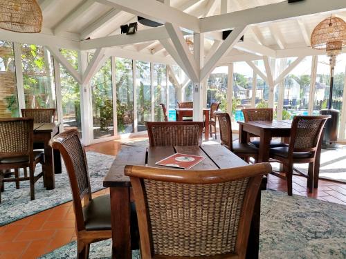 a dining room with tables and chairs and windows at Duna Parque Beach Club - Duna Parque Resorts & Hotels in Vila Nova de Milfontes