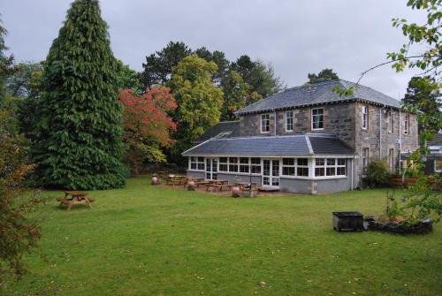 a large stone building with a yard with picnic tables at Columba House in Kingussie