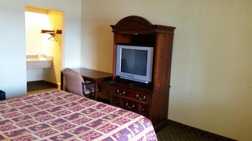 a hotel room with a bed and a tv on a cabinet at Travel Inn Motel in Hartford