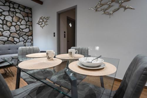 a dining room with two tables and chairs and a stone wall at Meteora vibes in Kalabaka