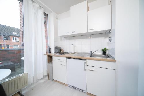 a kitchen with white cabinets and a sink at Studio Shiny - Zentral mit Balkon - Messe - Küche in Neuss