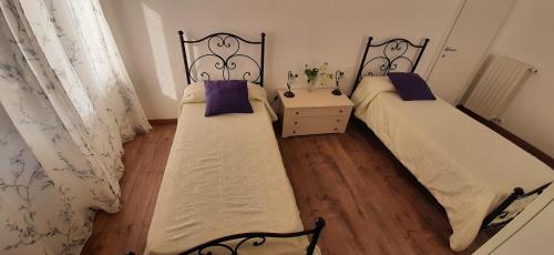 two twin beds in a room with wooden floors at Casa Al Lago in Bolsena
