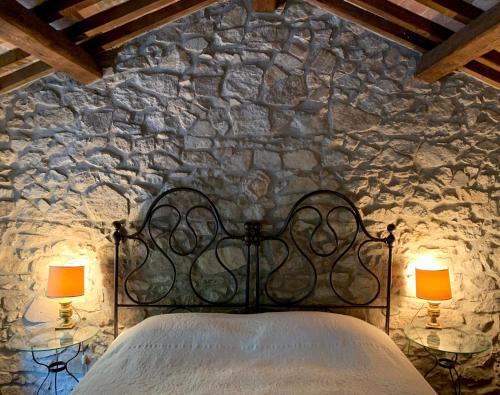 a bedroom with a stone wall with a bed and two lamps at Euganean Hills Natural Park: Casale Il Boschetto in Torreglia