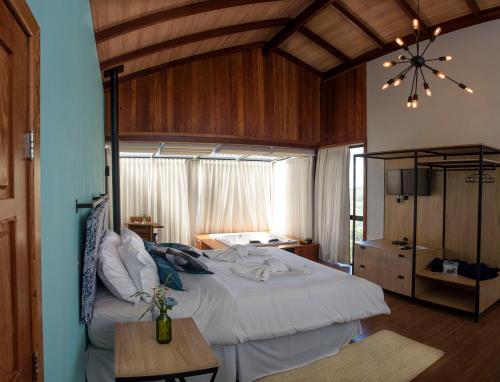 a bedroom with a large white bed and a table at ÁGUA MARINHA Pousada Caparao in Divisa