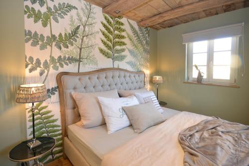 a bedroom with a bed with pillows and a wall with plants at Maison 1775 Ferien im historischen Bauernhaus, Wissembourg, Elsass in Ingolsheim