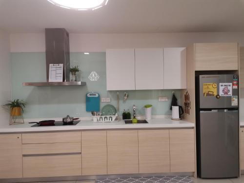 a kitchen with white cabinets and a stainless steel refrigerator at HINODE Geniehome 3BR free WIFI and CARPARK at Utropolis Shah Alam in Shah Alam