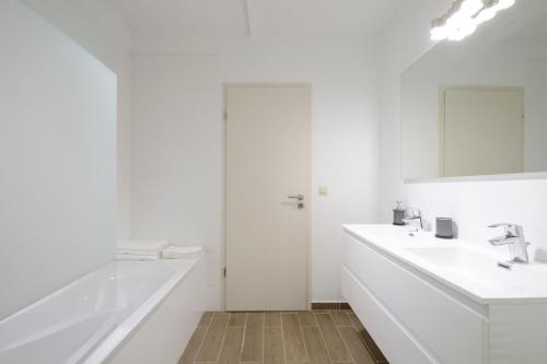 布魯塞爾的住宿－Ilot Sacre Apartments，白色的浴室设有2个盥洗盆和1个浴缸。