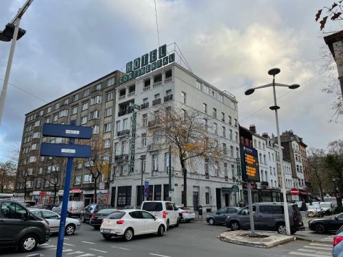 a large white building with cars parked in a parking lot at Hotel Continental Gare du Midi in Brussels