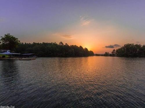 a sunset on a lake with a boat in the water at LAKEFRONT 7 MIN to OAKLAWN & 10 MIN to DOWNTOWN STR License #A22-0004 in Hot Springs