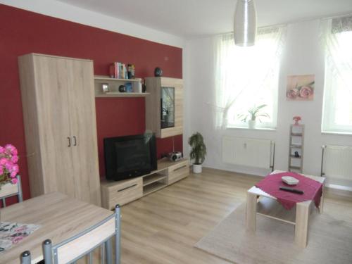 a living room with a tv and a table at Ferienwohnung Rosenflair in Schönebeck