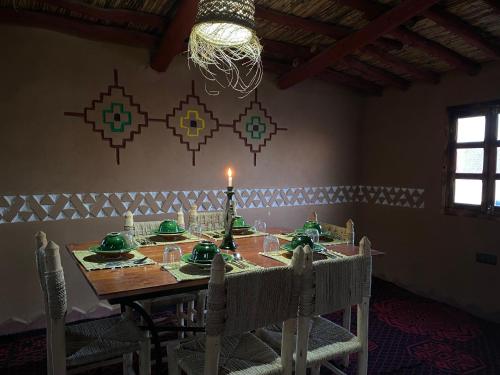 a dining room with a table with a candle on it at Camp Auberge Sahara Marokko in Mhamid