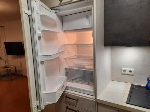 an empty refrigerator with its door open in a kitchen at Ferienwohnung Albus in Albertshausen