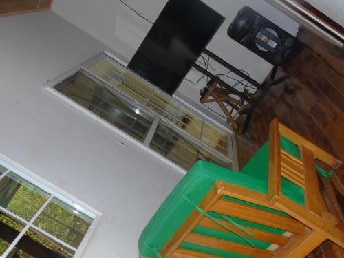 a room with a green chair and two windows at Hostal Villas Mexico in San Juan del Sur
