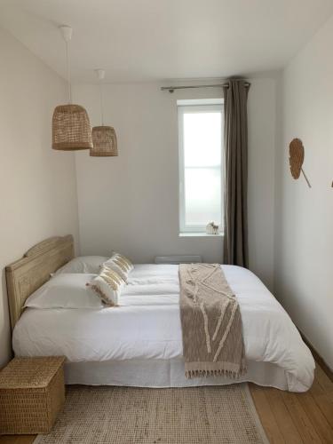 une chambre avec un lit avec des draps blancs et une fenêtre dans l'établissement LES JARDINS avec terrasse, à Amiens