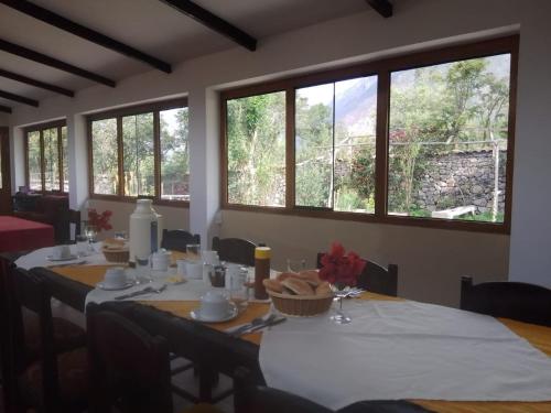 Casa de Mama Valle - Urubamba في أوروبامبا: غرفة طعام مع طاولة مع كراسي ونوافذ