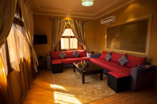 a living room with a red couch and a table at ApartHotel Nzaha in Tahannout