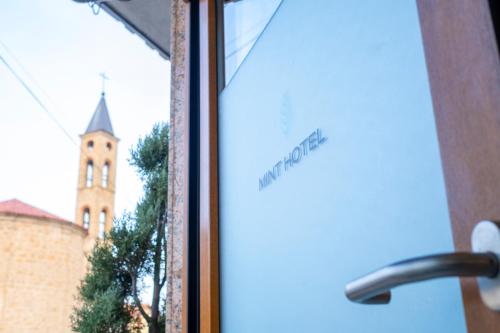 ventana con vistas a una iglesia con torre en Mint Hotel, en Prizren